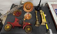 Full view of carnival glass pieces, brass candlesticks, model motorcycle, and lamps on black padded surface