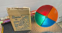 Rotating color wheel with colored sections and original box visible on the left side, showing the product name and model number.