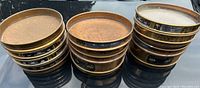 Multiple stacks of brass circular sieves showing various size labels, patina and handwritten markings on sides.