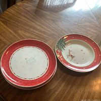 Four Portmeiron Christmas Wish plates and one bowl with festive designs on a wooden table.