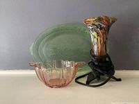 Three items shown including green oval platter, pink rose-shaped bowl, and Murano blown glass accent lamp with metal stand, with lamp cord wrapped around base.