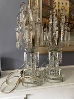 Pair of electrical crystal lights with faceted bases and multiple hanging prisms displayed on a white surface.