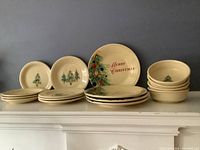Full set including large plates, medium plates, small plates, and bowls all with holiday Christmas tree designs and Merry Christmas text.