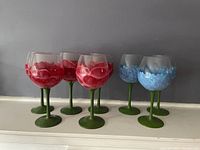 Full set of eight wine glasses, five with red flower design, three with blue flower design, all with green stem and base.