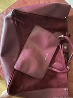 Deep wine leather and suede large tote bag with wristlet laying inside, showing color and materials.