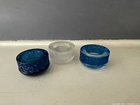 Three Swarovski crystal tea light holders displayed without candles, showing colors and design.