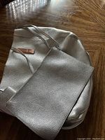 Photo showing matching silver leather wristlet pouch on or near tote bag