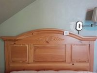 Front view of the full pine wood headboard showing the carved central design and panel layout.