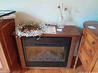 Infinity Flame faux fireplace with beaded wreath and reed scented oil holder on top