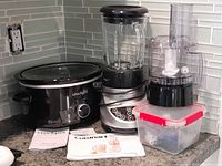 Full set showing Crockpot, Cuisinart blender, food processor, manuals, and plastic container with accessories