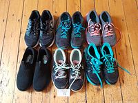 Five pairs of ladies sneakers arranged on wooden floor showing various styles and colors including Skechers slip-ons.