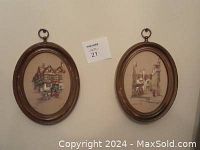 Pair of framed oval lithographs showing two historic inns with horse-drawn carriages, hung on a wall.