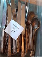 Grouped vintage knives with patterned handles and spoons partially visible showing patina and age wear.