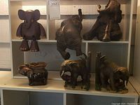 Collection of six elephant figurines including resin bookends, resin or metal-look elephants, wooden cartoonish elephant and ceramic votive holder
