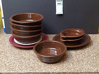 Full set of Fiesta Ware dishes shown including stacked bowls and plates with chocolate brown glaze.