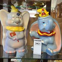 Photo showing two Dumbo cookie jars side by side on glass shelf, highlighting size and appearance.