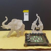 A view showing the clear acrylic elephant sculptures next to the bamboo tic tac toe board with zebra and elephant game pieces arranged on it.