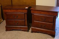 Photo of the front sides of the pair of dark wood 2-drawer side tables showing their overall design and condition.
