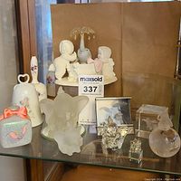 Wide view of all items in lot showing Snowbabies figurine, crystal and glass Disney Dumbo items, Precious Moments ceramic bell, and assorted crystal figurines.