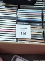 Photo showing a variety of music CD spines in jewel cases stacked in a cardboard box, including Lynyrd Skynyrd 8 Classic Albums and Alan Jackson 16 Biggest Hits.