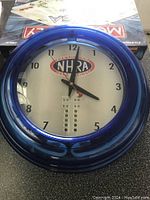 NHRA wall clock with blue frame and NHRA Championship Drag Racing logo on dial.