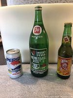 Photo showing all three commemorative bottles/can: 7Up 1978 Rose Bowl, Sun Drop Dale Earnhardt, and Woodstock '94 Pepsi can.