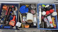 Three plastic totes filled with assorted garage supplies including tools, chemicals, and automotive items.