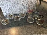 Wide shot of all 8 glasses showing horoscope animals, drag racing and beer branding