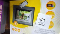 Close up image of Kodak EasyShare SV811 box showing 8-inch digital photo frame with 128MB memory and 800x600 resolution, with another item packaging partially visible underneath.