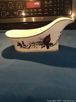 Side view of the Lenox wine caddy showing the cardinal bird painting and its curved design.