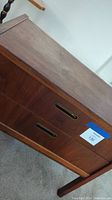 Side view of two-drawer wood accent table showing inset metal pulls and wood grain.
