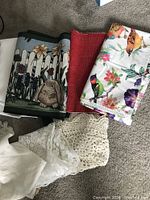 Photo showing folded assorted fabric pieces including a garden-themed fabric with bunny, red textured fabric, bird and floral print, and white lace fabric.