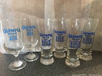 Six vintage Olympia Beer glasses six including two wine-style and four schooner-style glasses with blue logo.