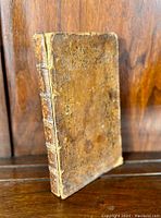 Spine and partial front cover of the book highlighting raised dentiles and leather texture with wear.