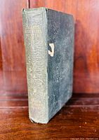 Front view of the 1850 book showing cloth binding, spine text, and wear including a torn cover spot.