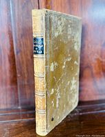 Front angled view showing spine with title label and raised bands, and worn leather cover with aging visible.