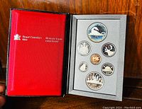 View of the open red and black Royal Canadian Mint presentation box showing 7 proof coins in foam insert. Coins obverse and reverse visible.