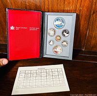 Full image of Royal Canadian Mint red case with 7 coins arranged in holder and specification sheet beside it.