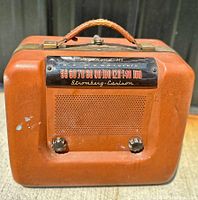 Front of vintage Stromberg Carlson 4061 tube radio showing frequency display, speaker grille, and two bakelite knobs with leather handle on top.