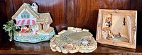 Wide view of three Pendelfin bunny base display figurines showing cottage, pond, and bunny couple framed piece