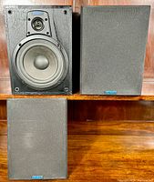 Pair of Jensen C-1 bookshelf speakers, one with grille attached and one grille removed, shown on a wooden surface.