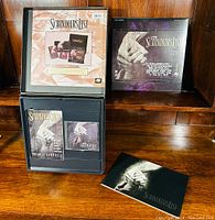 Front of open box showing multiple items inside including a booklet, inserts, and laserdisc cases.