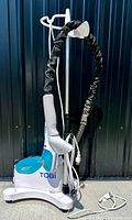 Full view of Tobi garment steamer unit showing base, telescopic pole, flexible hose with fabric sleeve, and handheld steamer head hanging on pole.
