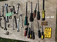 First photo showing assorted screwdrivers laid out with varying handle colors and sizes alongside a yellow Stanley bit set and some small wrenches.