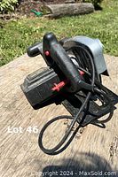 Close-up photo of the circular saw handle, motor housing, and attached power cord lying on a wooden surface outdoors.