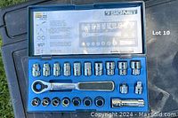 Photo showing open case with gear ratchet handle and assortment of sockets inside blue plastic case with clear top showing layout and brand markings