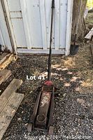 Full view of the red hydraulic floor jack standing upright showing the handle and base with wheels.