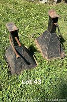 Pair of metal jack stands placed on grass showing worn surface and rust, providing overall condition view of the lot.