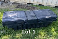 Wide shot of the black plastic pickup truck bed toolbox closed, showing its full length and top surface.