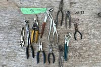 Multiple pliers and assorted hand tools laid out on a weathered wooden surface, showing various sizes and handle types.